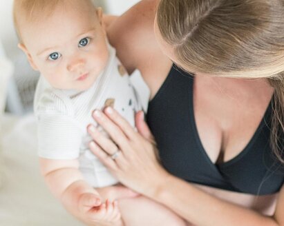 Ein Baby blickt von oben in die Kamera, während es von seiner Mutter gehalten wird.