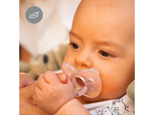 Baby benutzt den Medela SOFT SILICONE Schnuller in transparenter Farbe, während es den Finger der Mutter hält. Inklusive Symbol für „Leichtgewicht“.